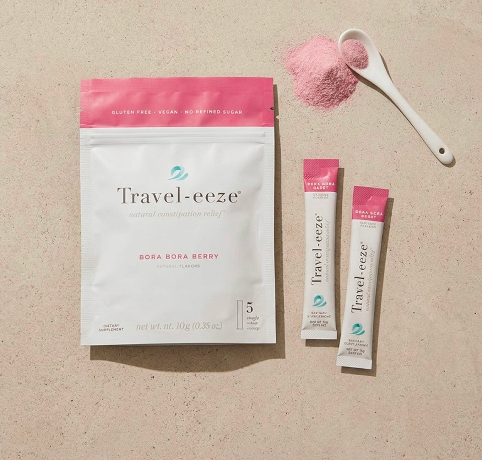 Travel-eeze product packaging with two sticks and a scoop of pink powder on a beige background