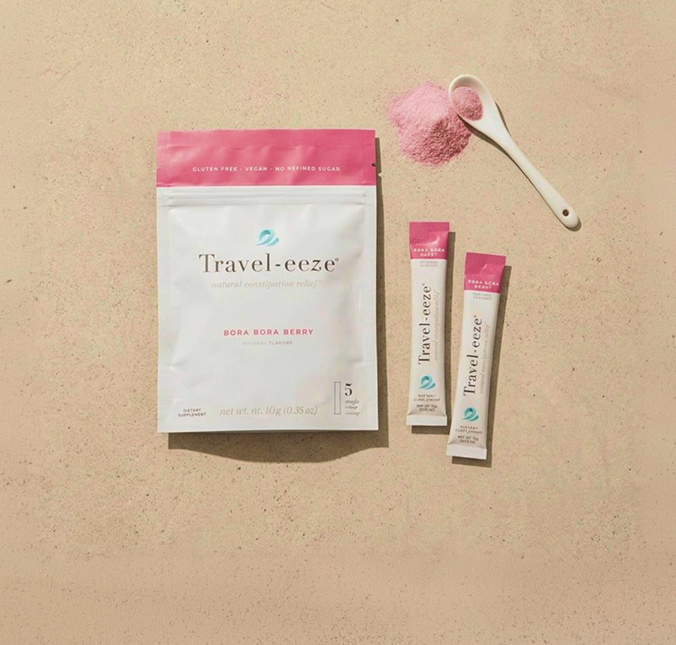 Travel-eeze product packaging with two sticks and a scoop of pink powder on a beige background